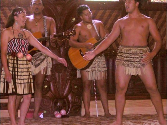 Skirts made of Phormium leaves being worn in performance before tourists in New Zealand.